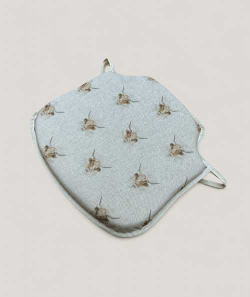 Spindle shaped chair pads in beige linen type fabric with a highland cow print