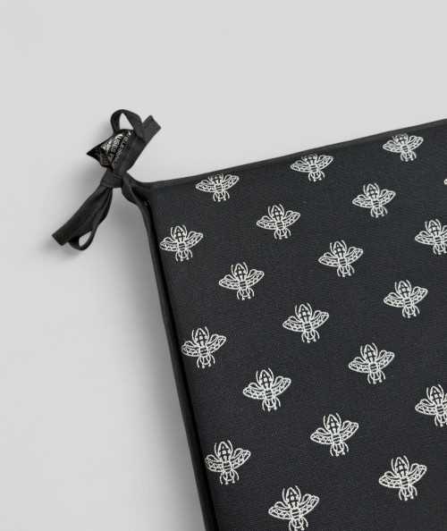 Square shaped black seat cushions with a small bee metallic print