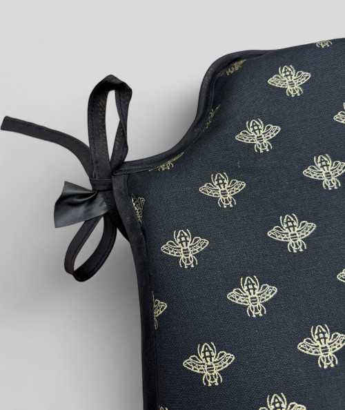 Black spindle shaped chair pads with an all over small gold bee print