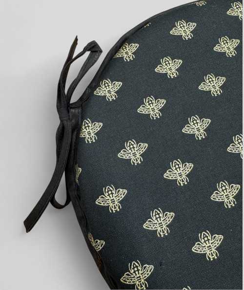 Black circular bistro chair pads with an all over small gold bee print